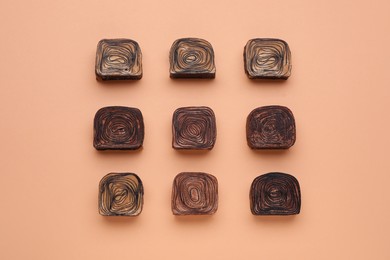 Different tasty chocolate candies on beige background, flat lay