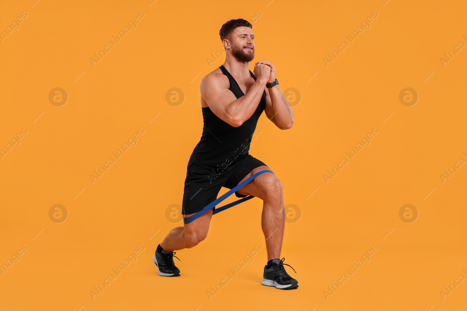 Photo of Young man exercising with elastic resistance band on orange background