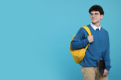 Photo of Portrait of student with backpack and laptop on light blue background. Space for text