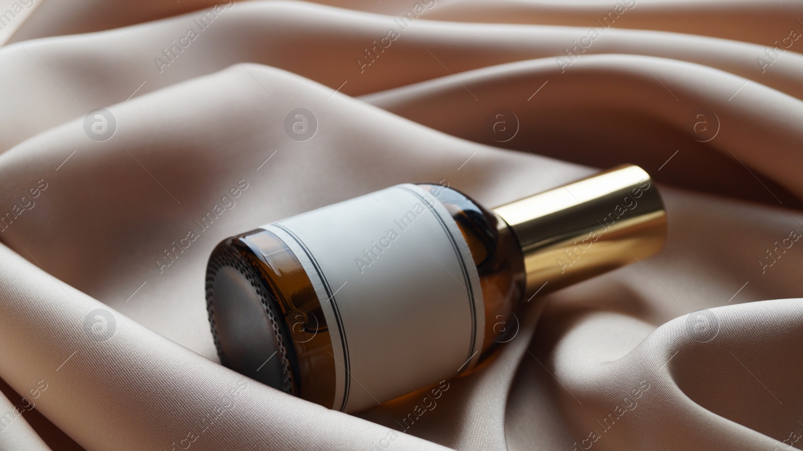 Photo of Luxury bottle of perfume on beige silk, closeup