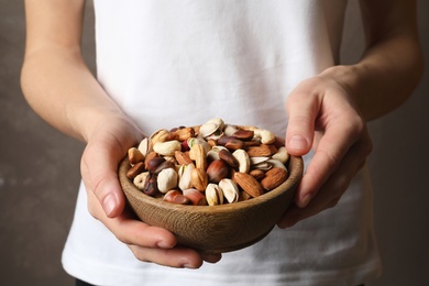 Woman holding bowl with organic mixed nuts, closeup
