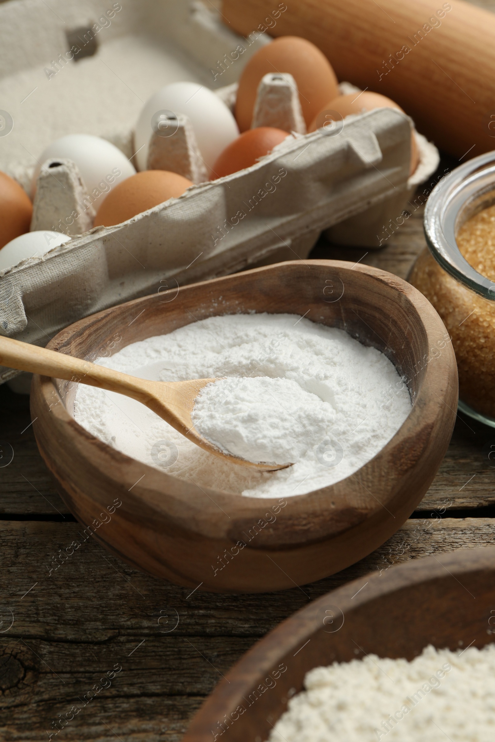 Photo of Baking powder and other ingredients for making dough on wooden table, closeup