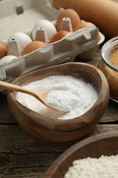 Baking powder and other ingredients for making dough on wooden table, closeup