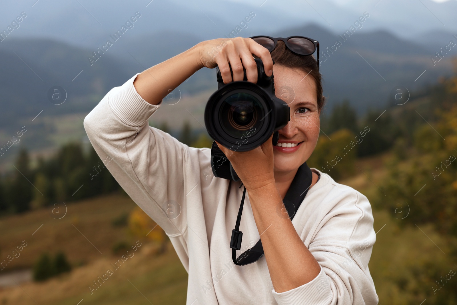 Photo of Professional photographer taking picture with modern camera in mountains