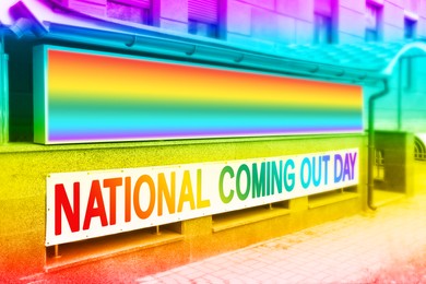 Image of Rainbow flag and text National Coming Out Day on banners outdoors, color toned