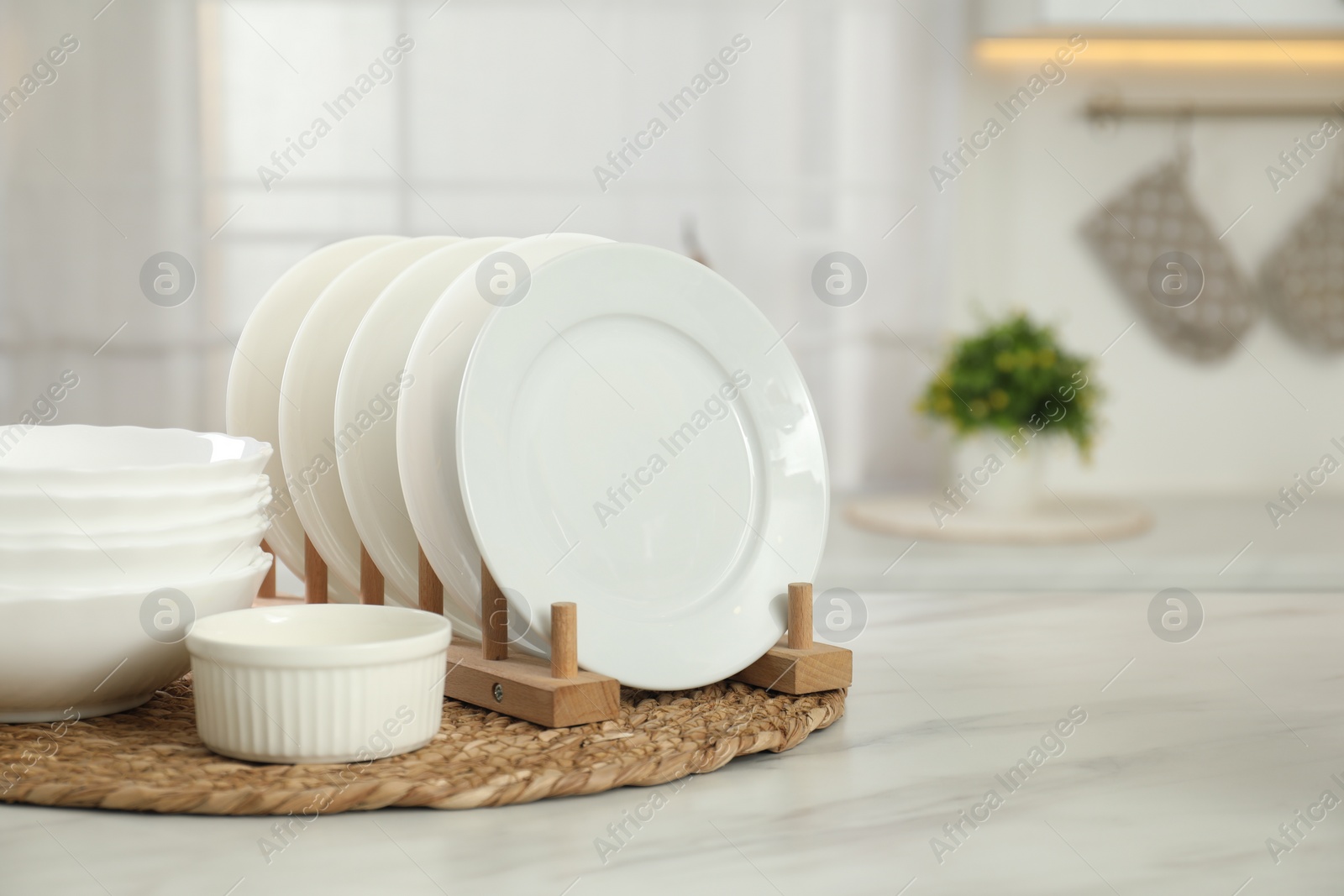 Photo of Clean plates and bowls on white marble table in kitchen, space for text
