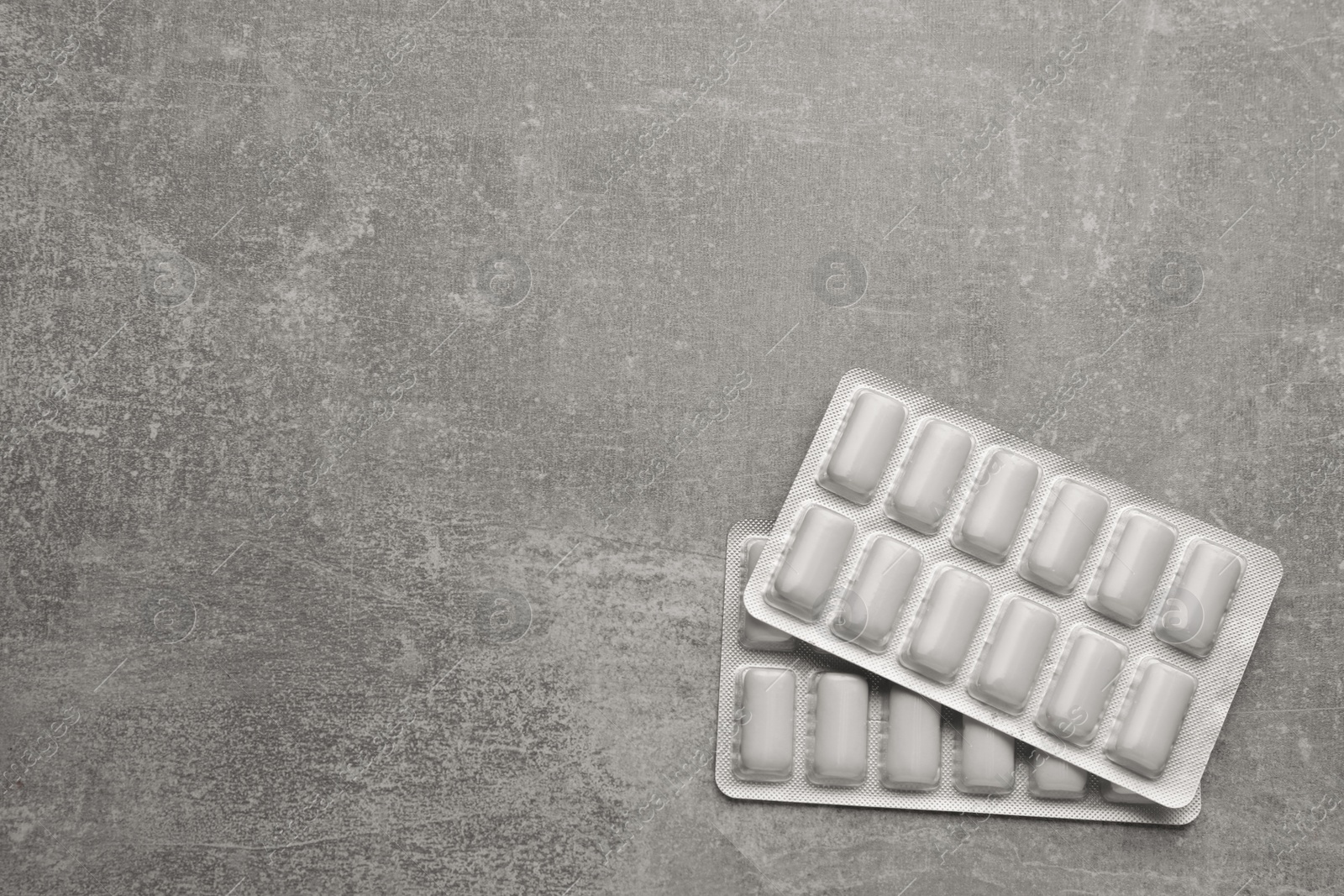 Photo of Blisters with chewing gums on light grey table, top view. Space for text