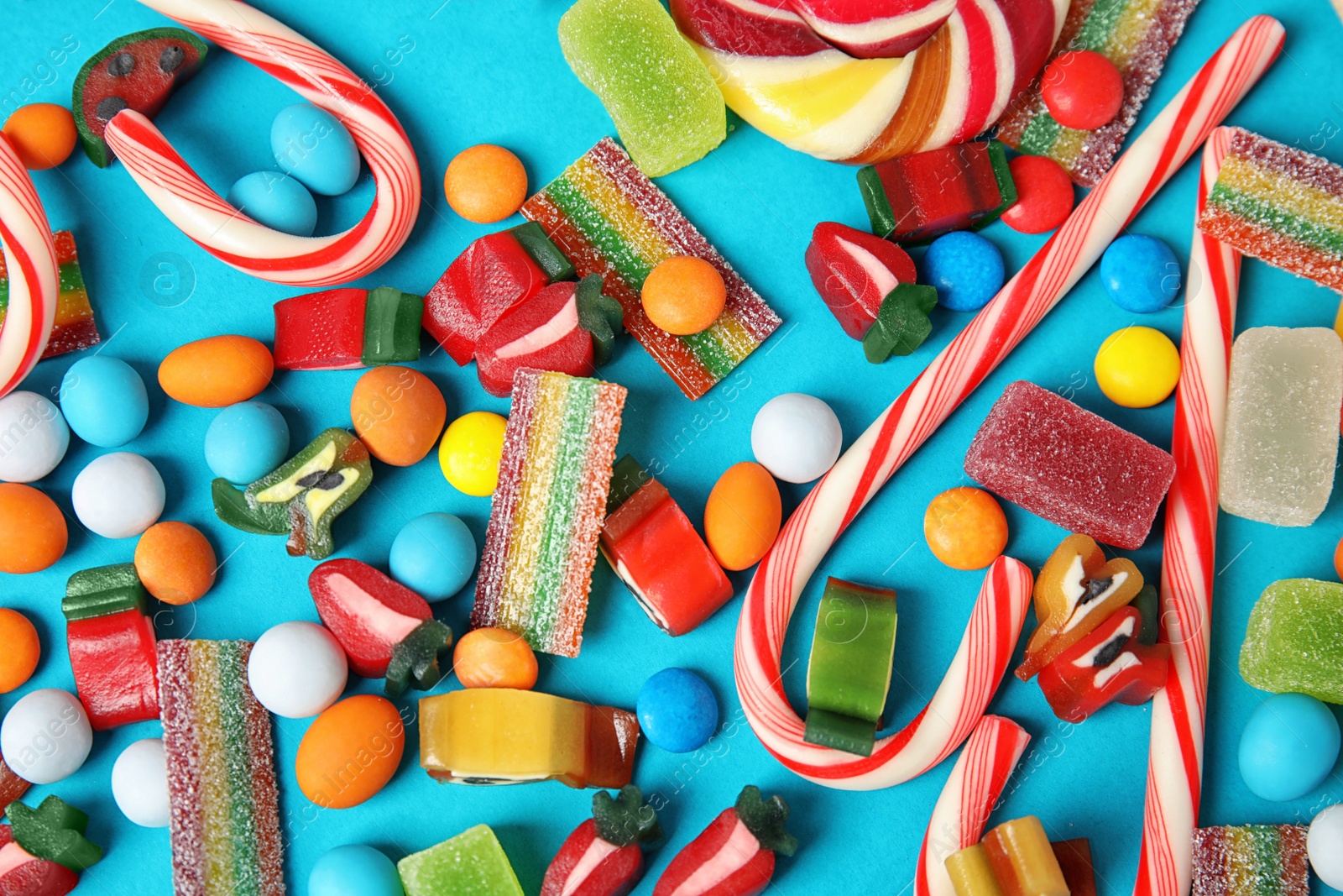 Photo of Many different yummy candies on color background, top view