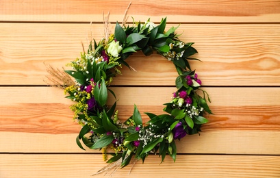 Photo of Beautiful wreath made of flowers and leaves on wooden background, top view