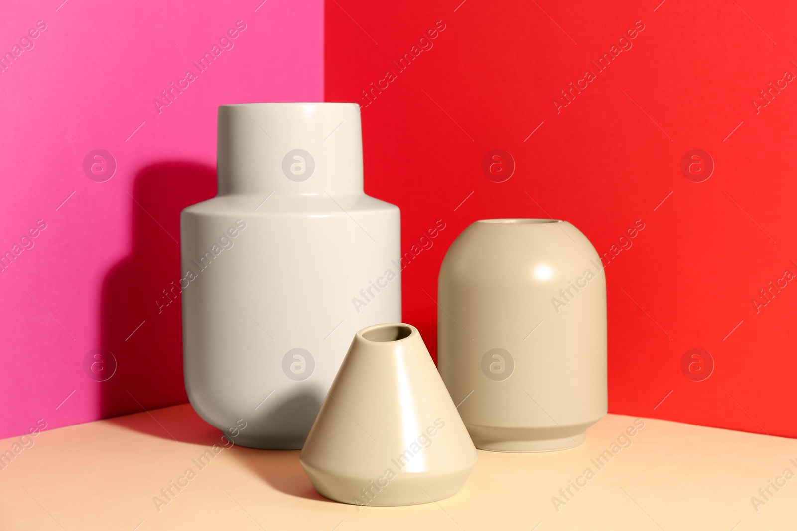 Photo of Stylish empty ceramic vases on color background