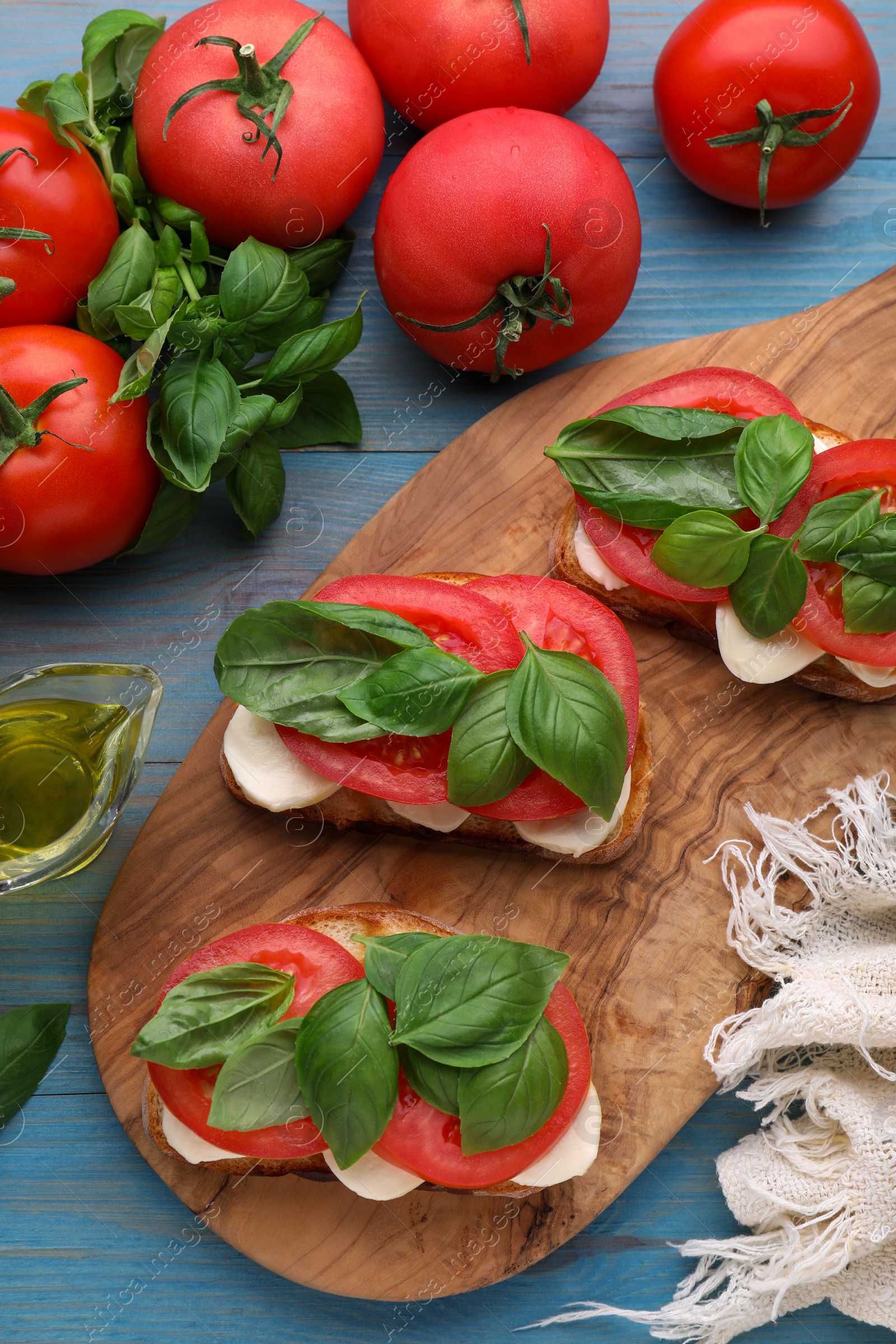 Photo of Delicious Caprese sandwiches with mozzarella, tomatoes and basil on light blue wooden table, flat lay