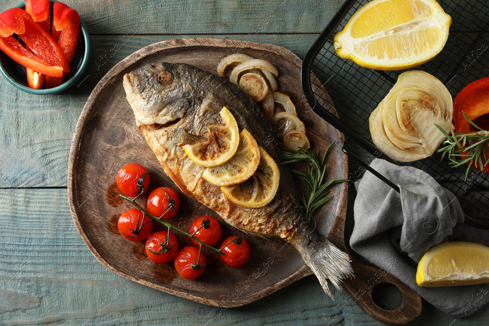 Photo of Delicious dorado fish with vegetables served on wooden table, flat lay