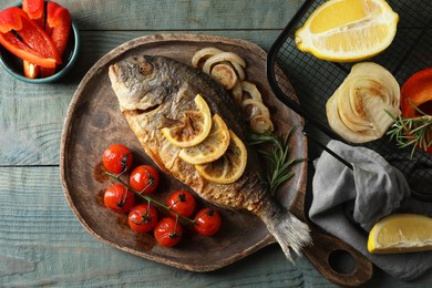 Delicious dorado fish with vegetables served on wooden table, flat lay