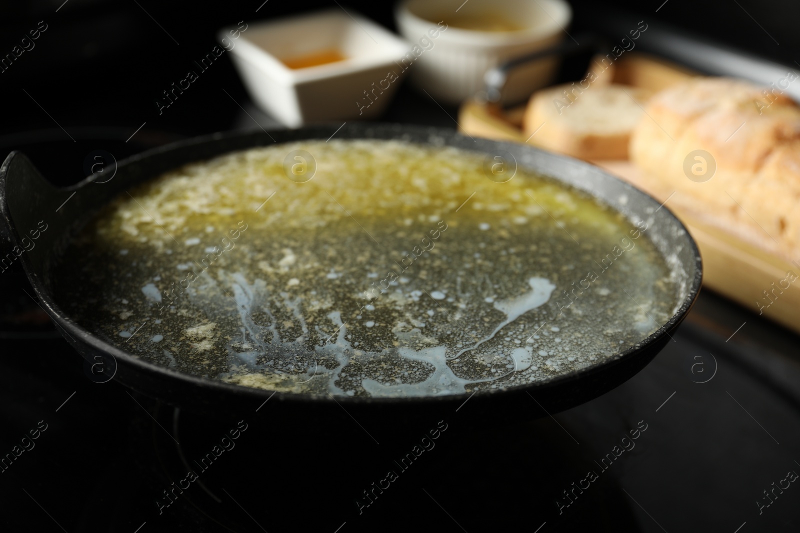 Photo of Melted butter in frying pan on black table, closeup