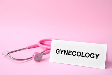 Card with word Gynecology and stethoscope on color background