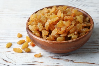 Photo of Bowl with raisins on wooden table. Dried fruit as healthy snack