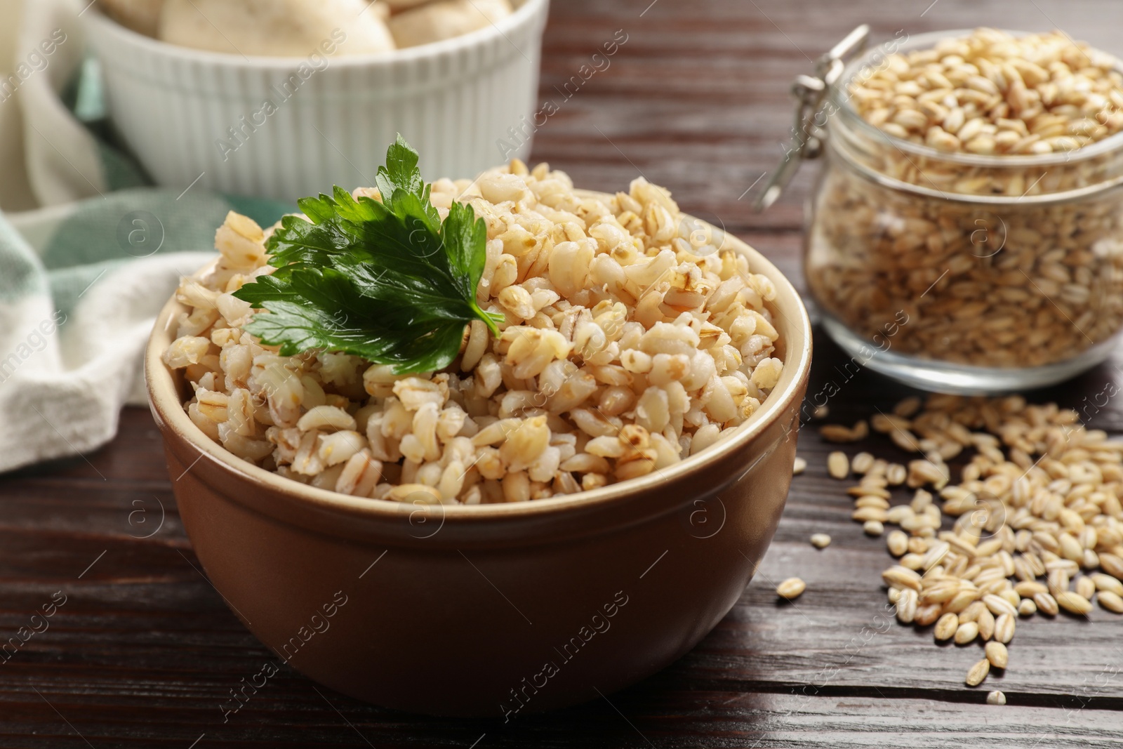 Photo of Delicious pearl barley with parsley in bowl on wooden table, closeup