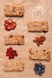 Different tasty granola bars and ingredients on parchment paper, flat lay