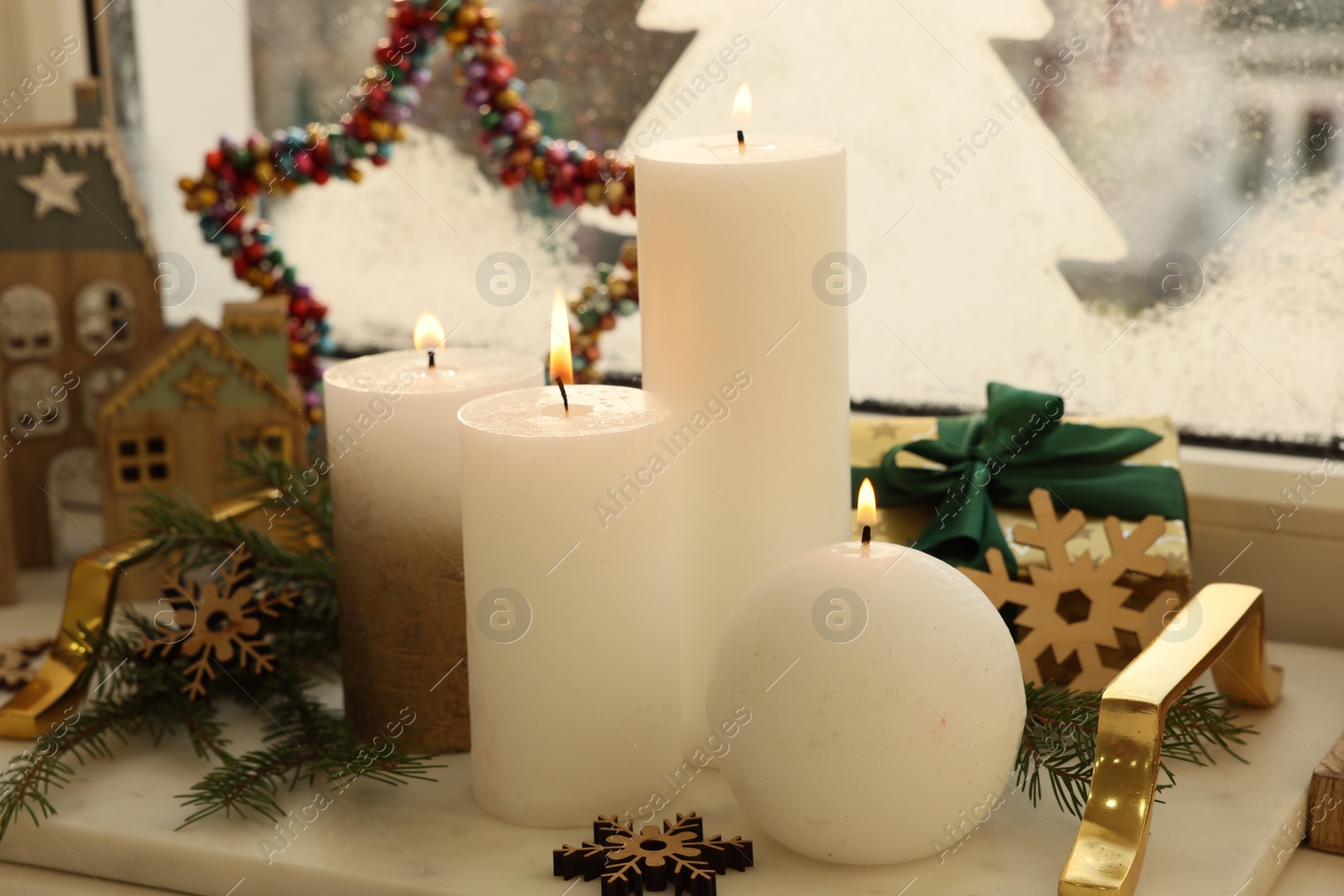 Photo of Beautiful burning candles with Christmas decor on windowsill indoors