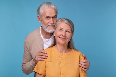 Portrait of affectionate senior couple on light blue background