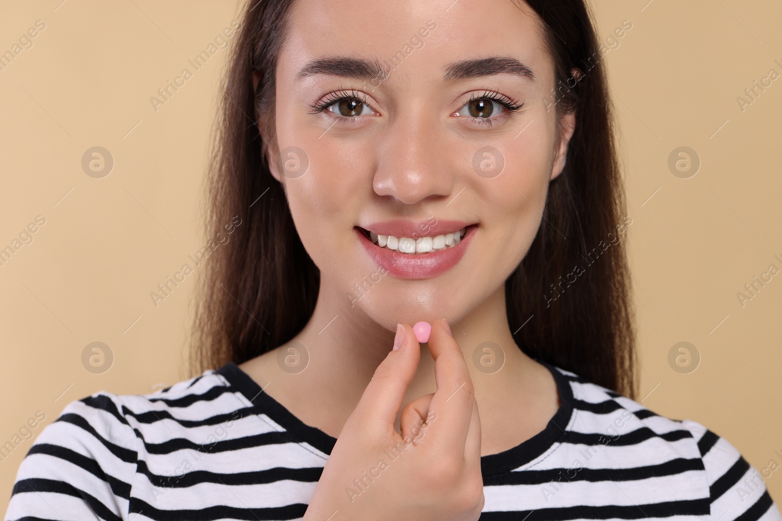 Photo of Happy woman taking pill on beige background