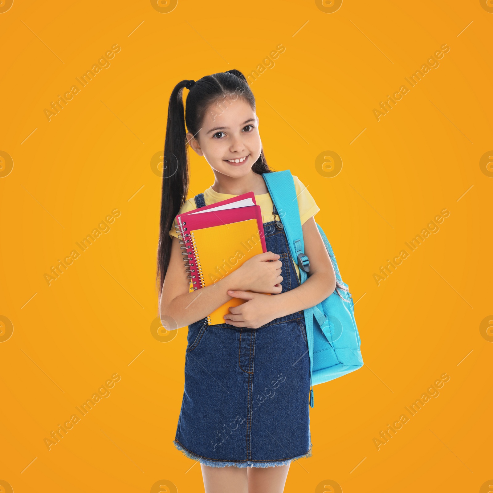 Image of Little girl with school stationery on yellow background