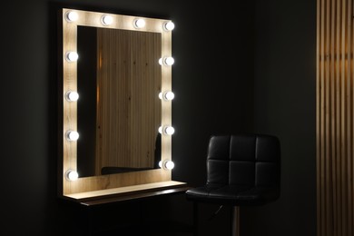 Photo of Beautiful mirror with light bulbs and chair in makeup room