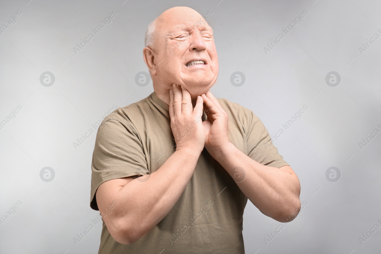 Photo of Senior man suffering from sore throat on light background. Enduring pain