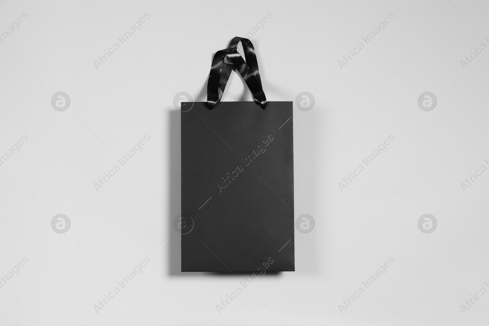 Photo of One black paper shopping bag on grey background, top view