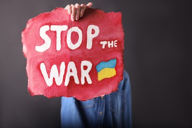 Woman holding poster with words Stop the War on black background, closeup