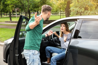 Man arguing with woman in broken car