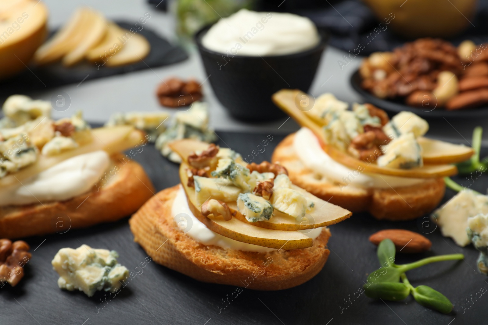 Photo of Delicious bruschettas with cheese, pear and nuts served on table, closeup