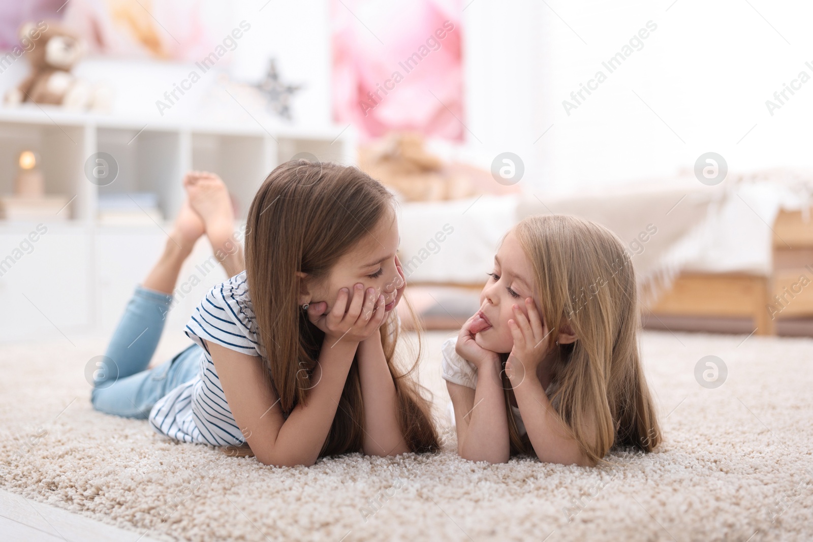 Photo of Cute little sisters on floor at home