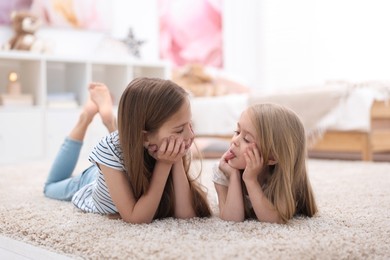 Cute little sisters on floor at home