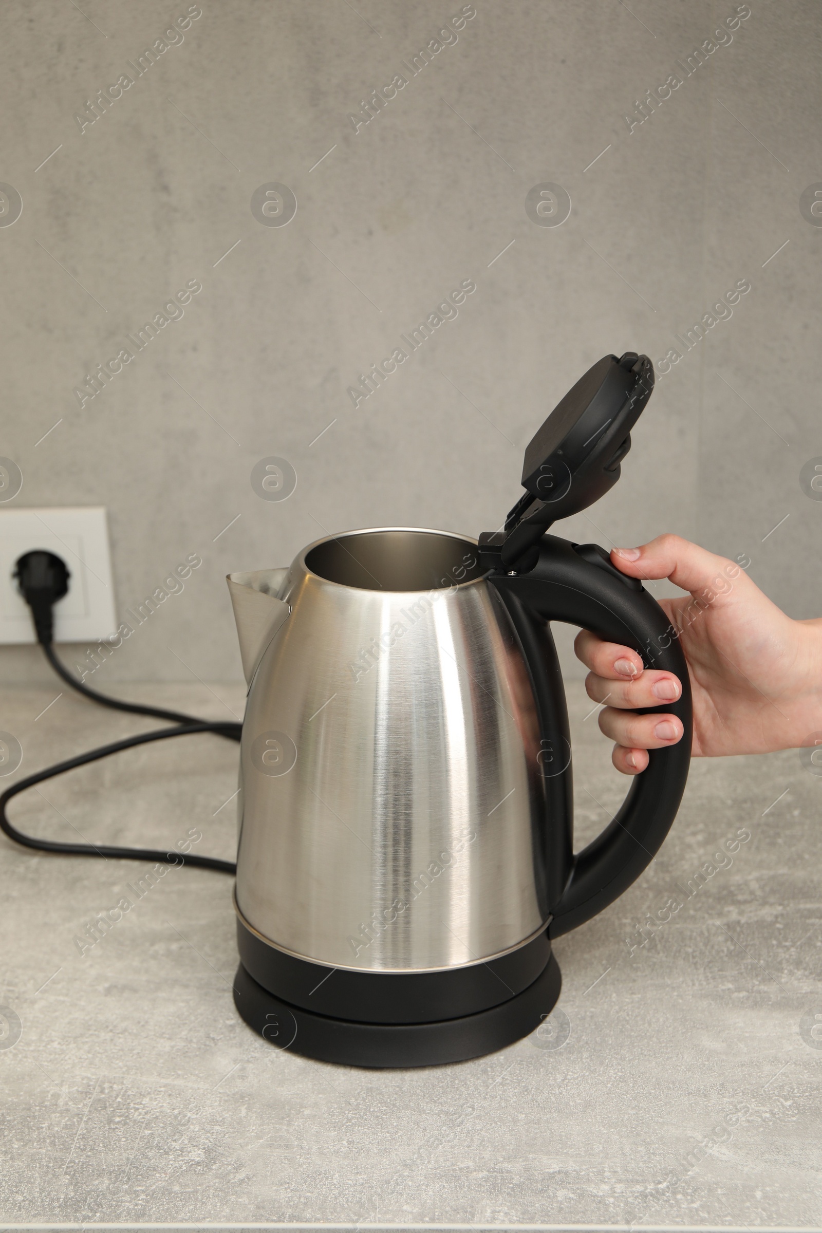 Photo of Woman with electric kettle in kitchen, closeup