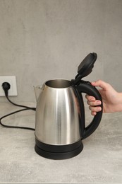 Photo of Woman with electric kettle in kitchen, closeup