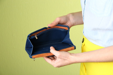 Photo of Woman showing empty wallet on light green background, closeup