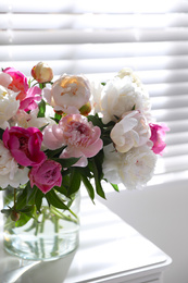 Photo of Beautiful peonies in vase on table near window indoors