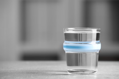 Photo of Glass of pure water on light grey table indoors, space for text