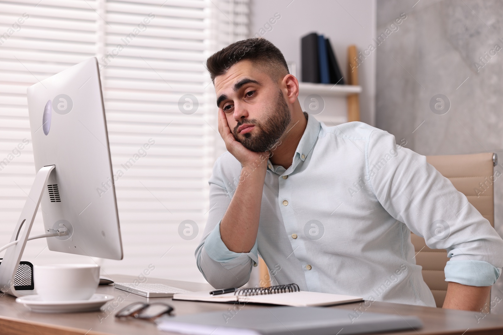 Photo of Overwhelmed man sitting at table in office