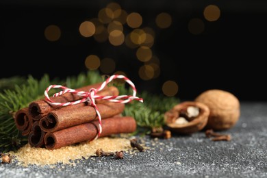 Different aromatic spices and fir branches on grey textured table, closeup. Space for text