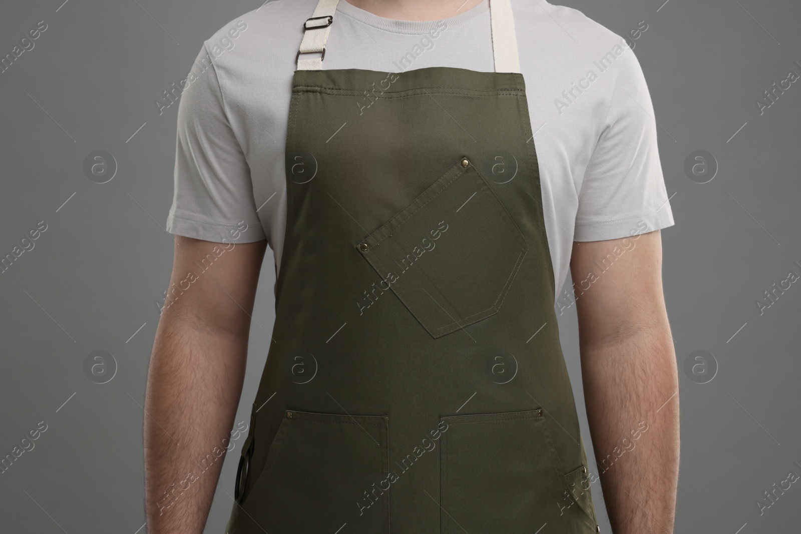 Photo of Man in kitchen apron on grey background, closeup. Mockup for design