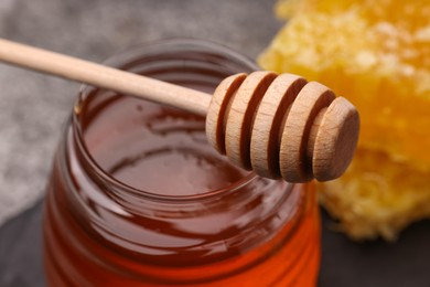 Photo of Sweet golden honey in jar and dipper on table, closeup