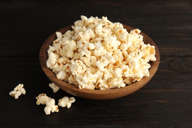 Photo of Bowl of tasty popcorn on wooden background