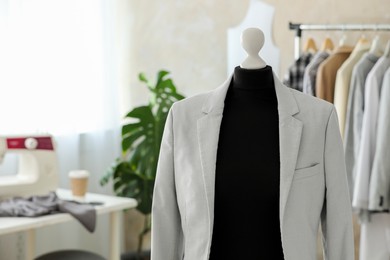 Photo of Mannequin with stylish jacket in tailor shop, space for text