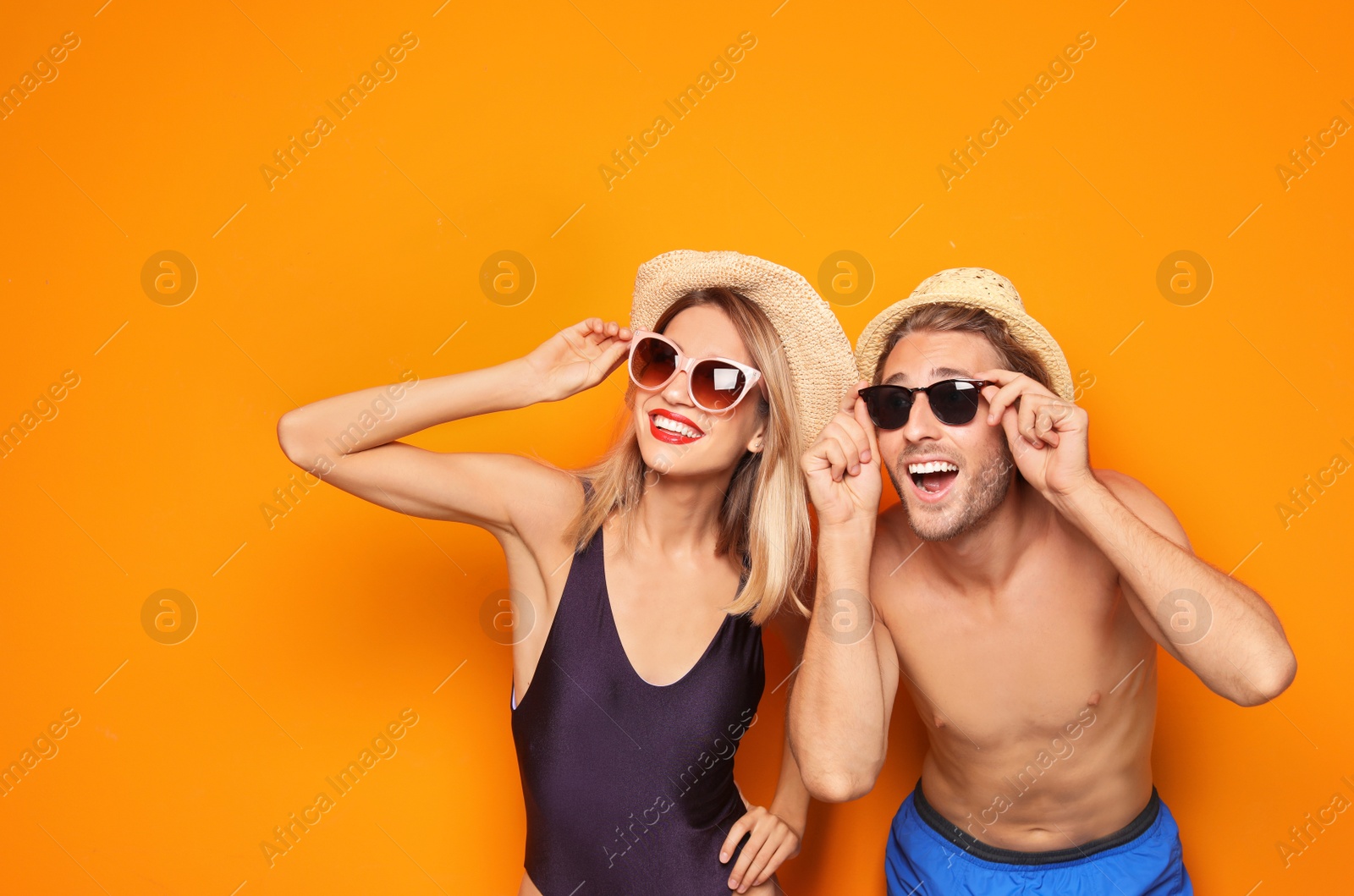 Photo of Happy young couple in beachwear and sunglasses on color background