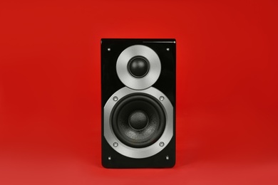 Modern powerful audio speaker on red background