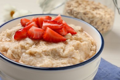 Photo of Tasty oatmeal porridge with strawberries on table, closeup