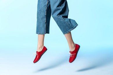 Photo of Woman in stylish shoes jumping on color background, closeup