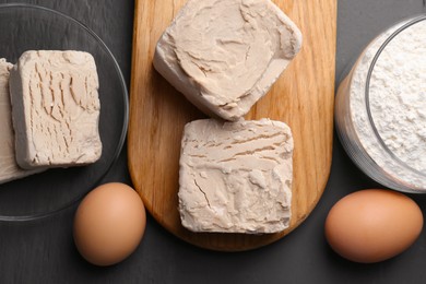 Compressed yeast, eggs and flour on grey wooden table, flat lay